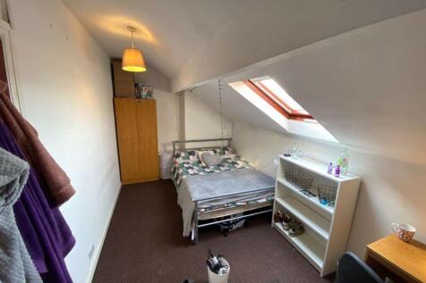 A cozy attic bedroom featuring a single bed ben...
