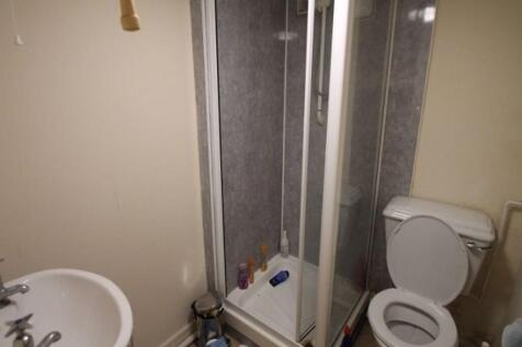 A compact bathroom featuring a corner shower un...