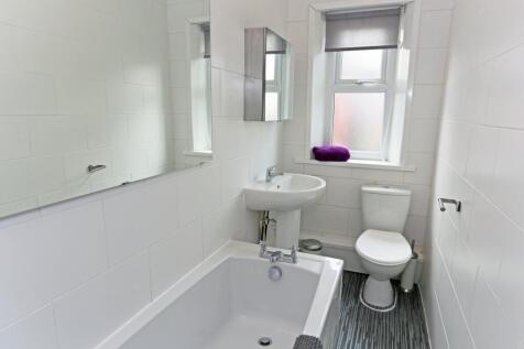 Bright and clean bathroom featuring a bathtub, ...