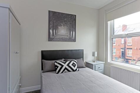 A cozy and well-lit single bedroom featuring a ...