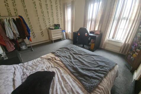 A spacious master bedroom featuring a comfortab...