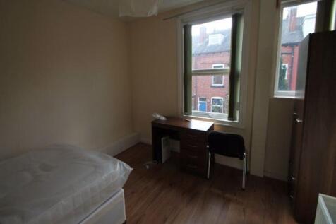 A cozy, well-lit single bedroom featuring a bed...