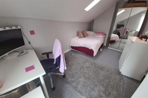 A bright and cozy bedroom featuring a neatly ma...