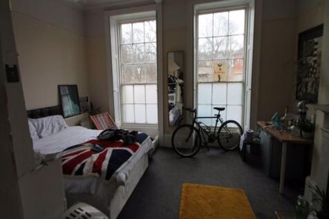 A cozy bedroom featuring two large windows that...