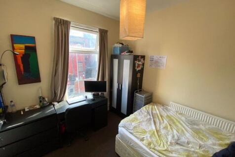 A cozy bedroom featuring a single bed with neat...