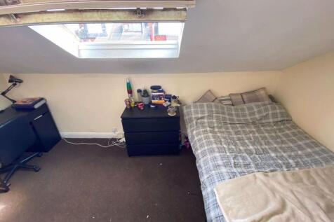 A cozy bedroom featuring a single bed with a ch...