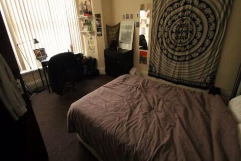 A cozy bedroom featuring a neatly made bed with...