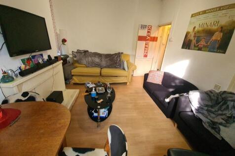 A cozy living room featuring a black sofa, a ye...