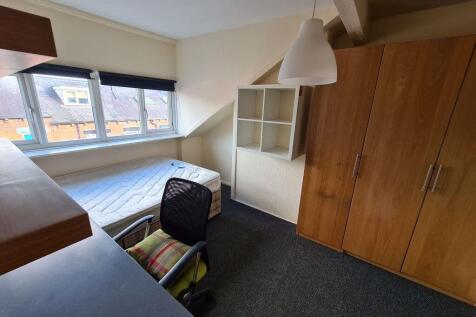 A cozy single bedroom featuring a large window ...