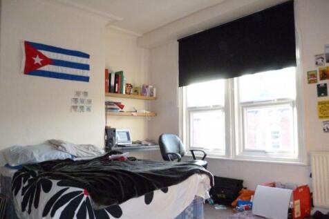 A cozy student bedroom featuring a bed with bed...