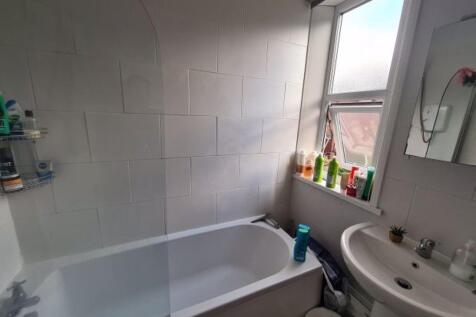 A clean and bright bathroom featuring a bathtub...