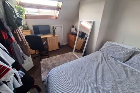 A cozy bedroom with a neatly made bed, a mirror...