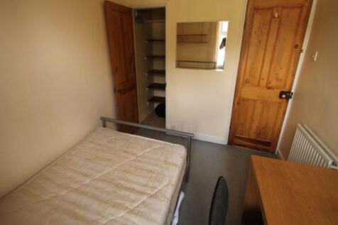 A cozy student bedroom featuring a bed and basi...