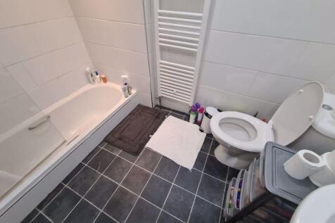 A clean and bright bathroom featuring a bathtub...