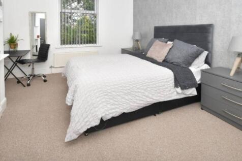 A modern, well-lit bedroom featuring a large be...