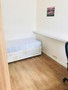 A small, tidy room featuring a single bed with ...