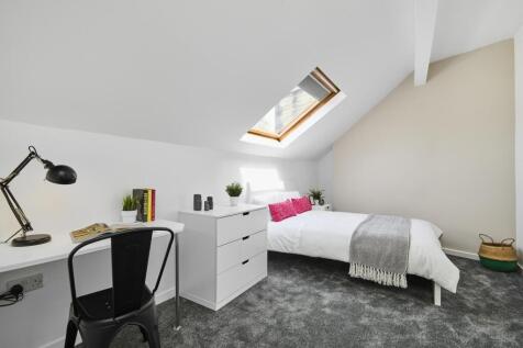 A bright and tidy bedroom featuring a comfortab...