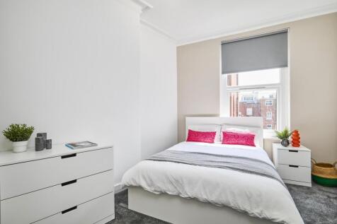 A bright and tidy bedroom featuring a comfortab...