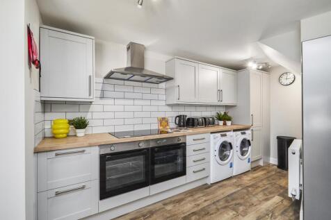 A modern and bright kitchen featuring white cab...