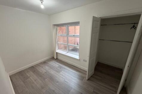 A bright and simply furnished bedroom with a la...