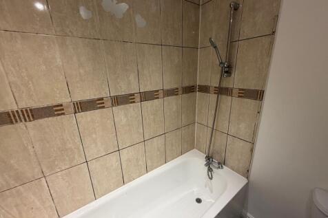 A clean bathroom featuring a beige tiled wall w...