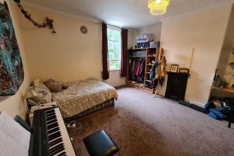 A cozy bedroom featuring a single bed, a window...