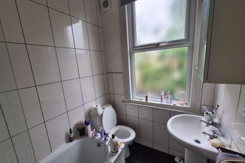 A clean and bright bathroom featuring a bathtub...