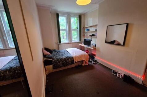 A cozy single bedroom featuring a bed, a window...