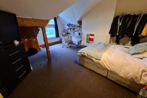 A cozy bedroom with a bed, some clothing hangin...