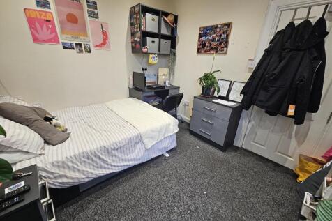 A well-maintained bedroom with a large bed, des...