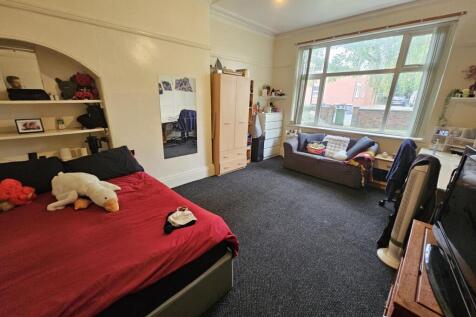 Spacious and well-lit master bedroom with a com...