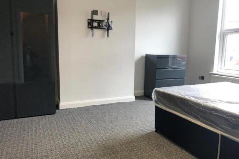 A modest single bedroom featuring a bed, window...