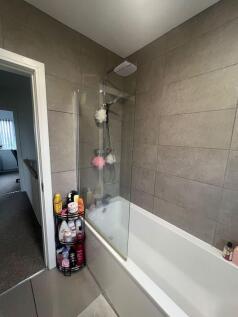 Modern bathroom with tiled walls, a white batht...