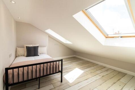 Bright attic bedroom with a sloped ceiling and ...