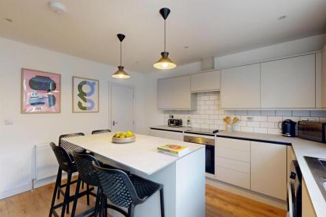 Modern and well-lit kitchen with chic white cab...