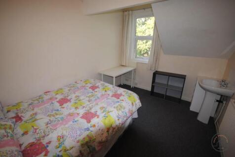 A cozy single bedroom featuring a bed with a co...