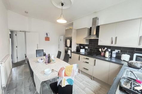 Bright modern kitchen with white cabinetry, bla...