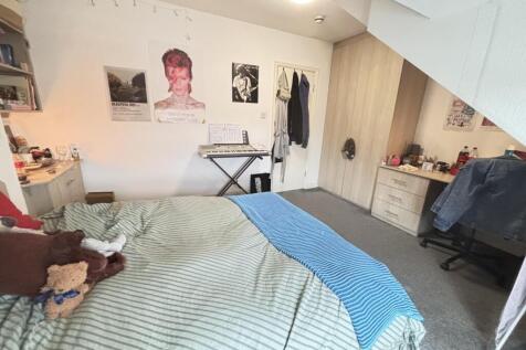 Cozy double bedroom with a made bed, bedside sh...