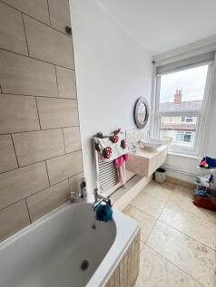 Bright, modern bathroom with a tiled bathtub, w...