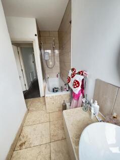 Bright tiled bathroom with a bath and overhead ...