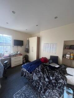 A cozy single bedroom featuring a bed with a pa...