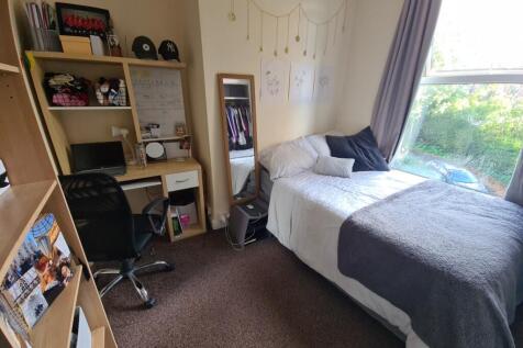 A cozy single bedroom featuring a neatly made b...