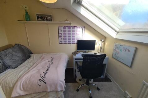 A cozy bedroom featuring a bed with a pink duve...