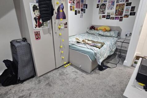 A cozy bedroom with a neatly made bed, personal...