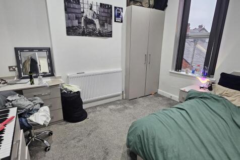 A cozy bedroom featuring a neatly made bed by t...