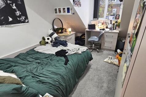 A cozy single bedroom with a neatly made bed, a...