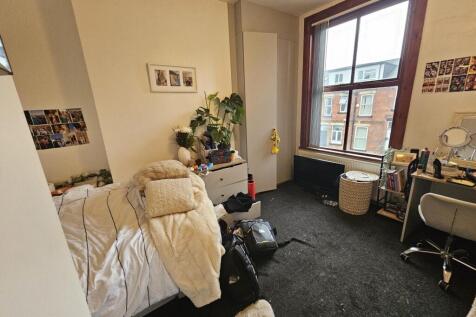 A bright and cozy bedroom featuring a large win...