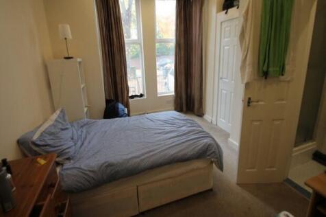 A cozy bedroom featuring a single bed, a window...