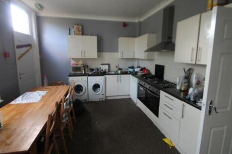 A modern kitchen with white cabinetry and appli...