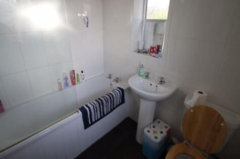 A clean and bright bathroom featuring a bathtub...
